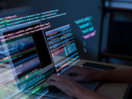 Hands working on a laptop showing codes.